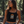 Tan, fit brunette girl wearing black tank top set in a forest scene.